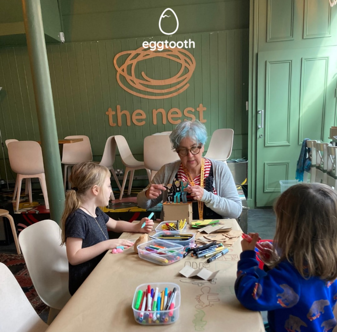 A woman running a crafting workshop with two young children