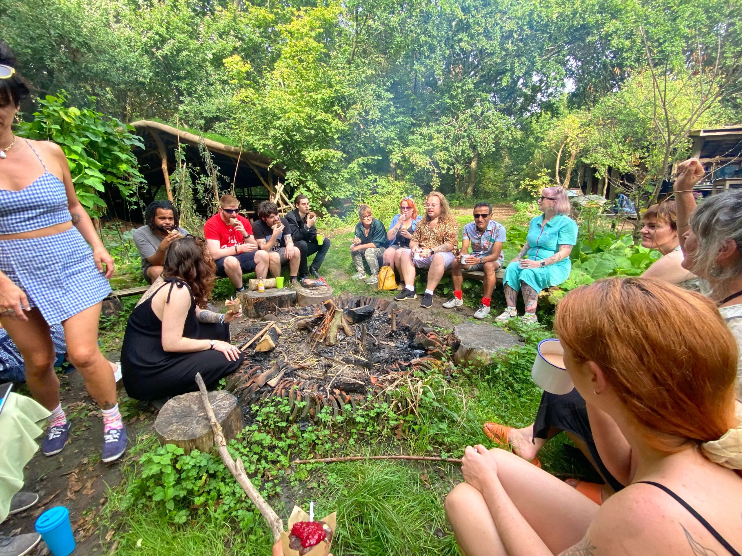A group of people sitting around a campfire in the daytime