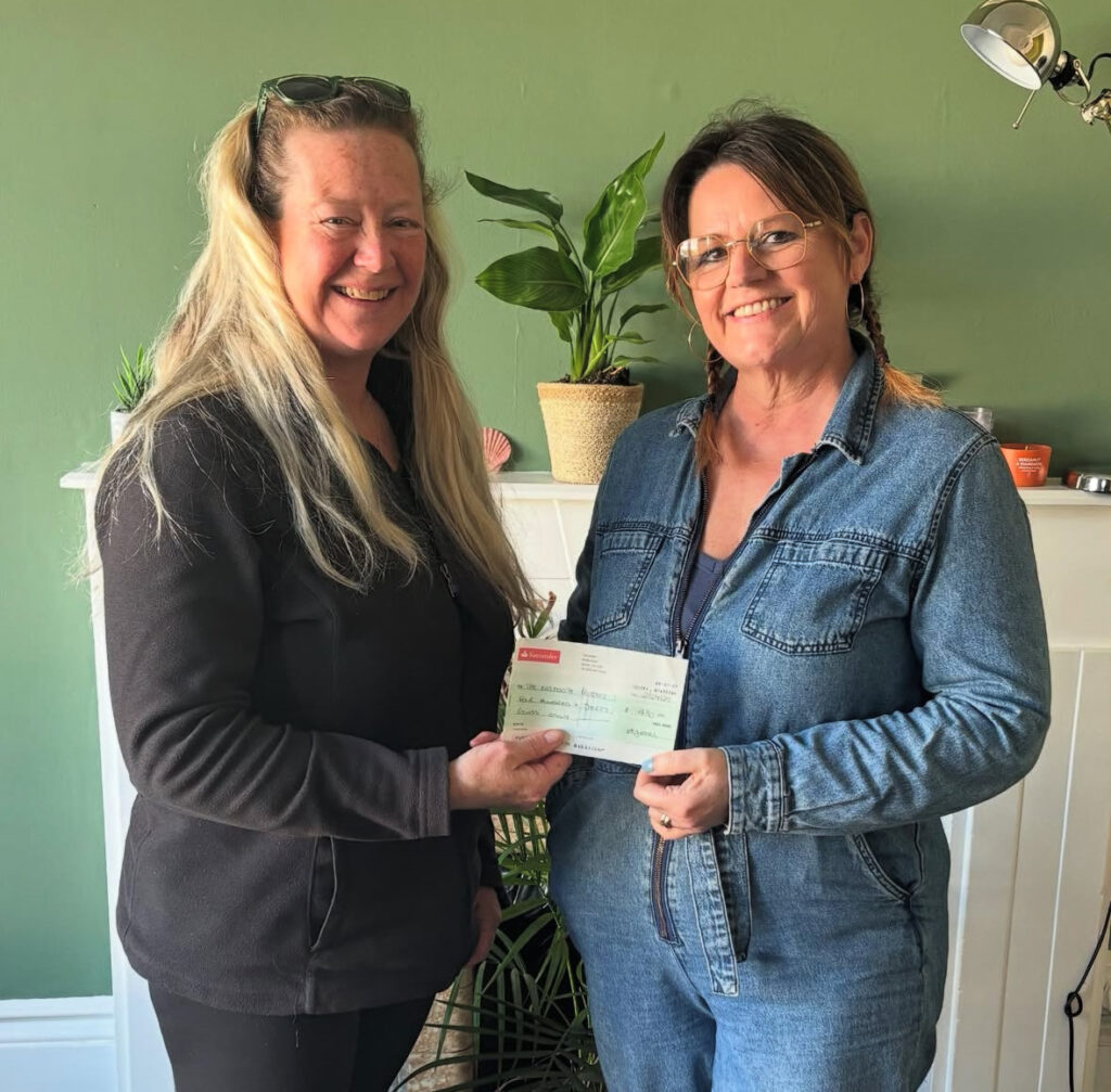 Two people exchanging a fundraising cheque